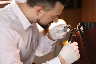 Photo of Appraiser with loupe evaluating leather bag indoors