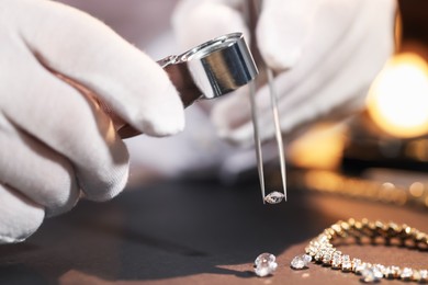 Photo of Appraiser with loupe evaluating gemstone at table indoors, closeup