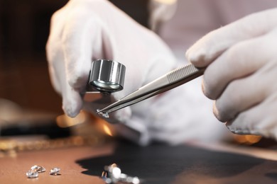 Photo of Appraiser with loupe evaluating gemstone at table indoors, closeup