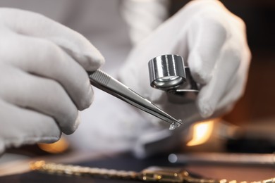 Photo of Appraiser with loupe evaluating gemstone at table indoors, closeup