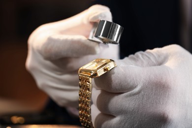 Photo of Appraiser with loupe evaluating luxury wristwatch indoors, closeup