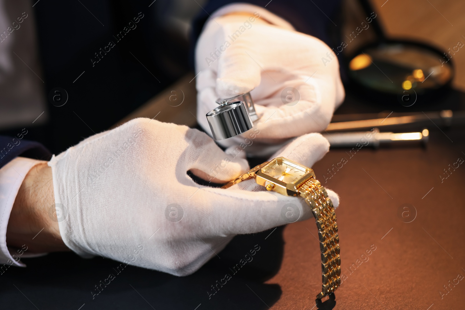 Appraiser with loupe evaluating luxury wristwatch at table, closeup Photo of Appraiser with loupe evaluating luxury wristwatch at table, closeup