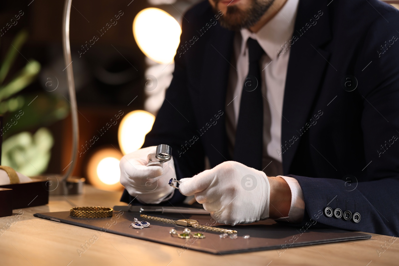Appraiser with loupe evaluating ring at table indoors, closeup Photo of Appraiser with loupe evaluating ring at table indoors, closeup