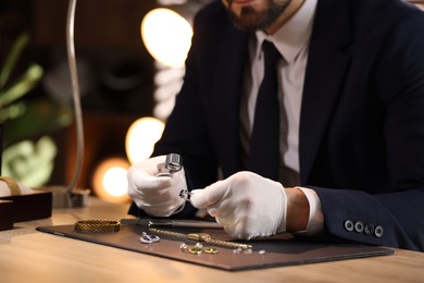 Photo of Appraiser with loupe evaluating ring at table indoors, closeup
