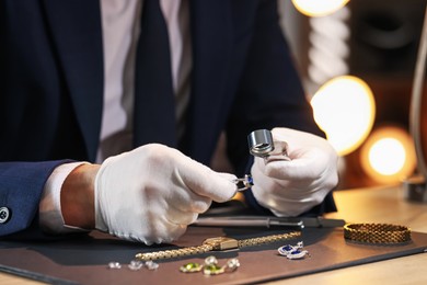 Photo of Appraiser with loupe evaluating ring at table indoors, closeup
