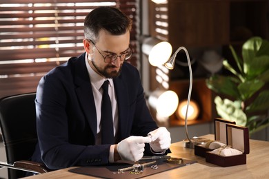 Photo of Appraiser working with luxury ring at table indoors
