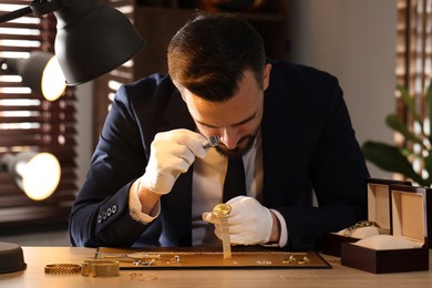Photo of Appraiser with loupe evaluating luxury wristwatch at table indoors