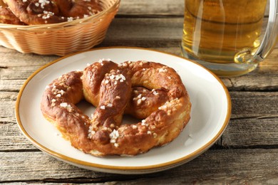 Photo of Tasty pretzel and beer on wooden table, closeup
