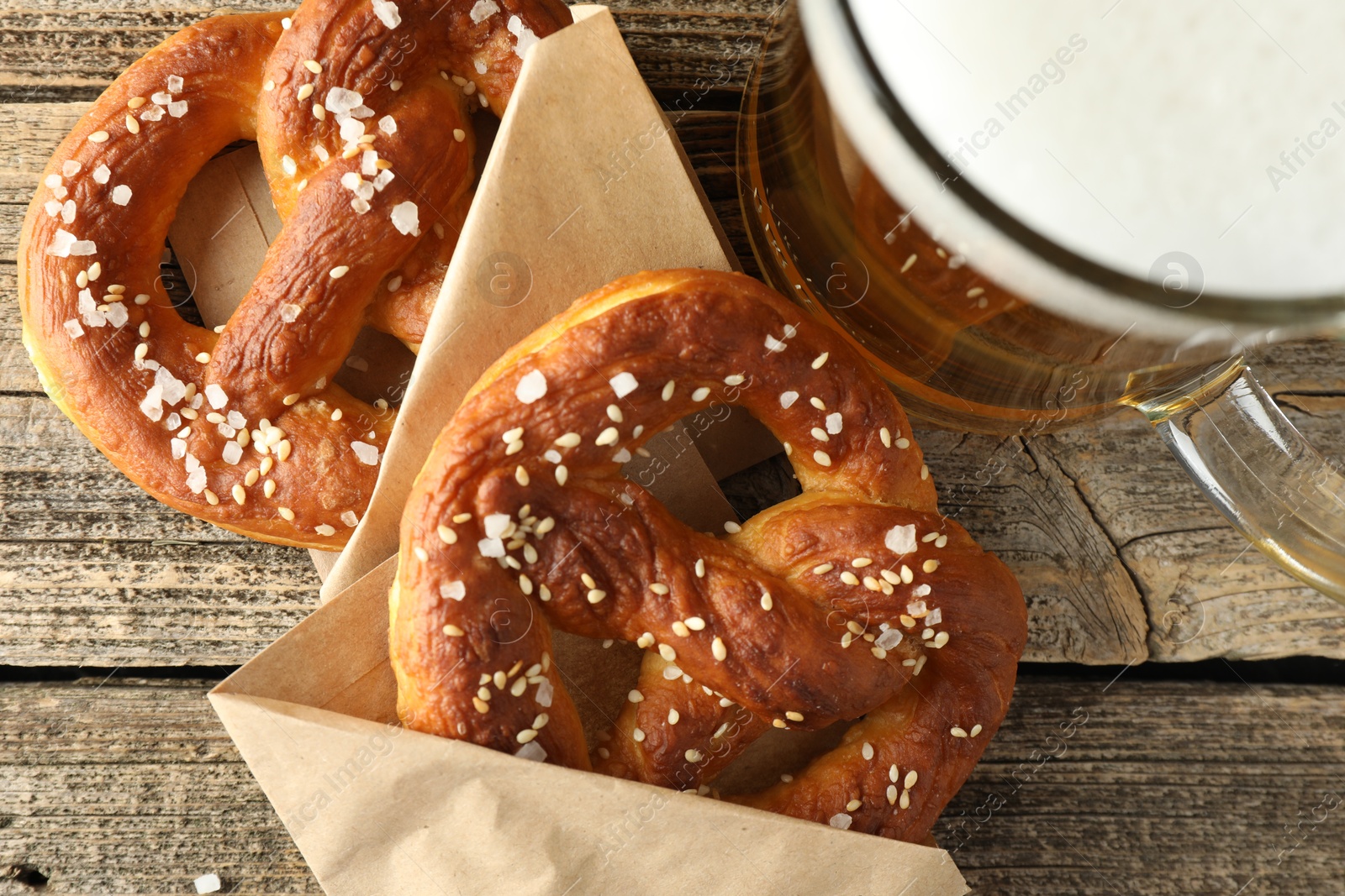 Tasty pretzels and glass of beer on wooden table, flat lay Photo of Tasty pretzels and glass of beer on wooden table, flat lay