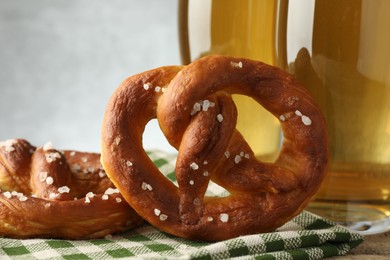 Photo of Tasty pretzels and glasses of beer on table against grey background, closeup