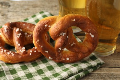 Photo of Tasty pretzels and glasses of beer on wooden table, closeup