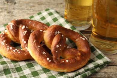 Photo of Tasty pretzels and glasses of beer on wooden table, closeup