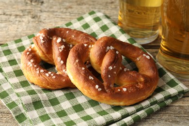 Photo of Tasty pretzels and glasses of beer on wooden table, closeup