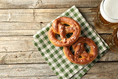 Photo of Tasty pretzels and glasses of beer on wooden table, flat lay. Space for text