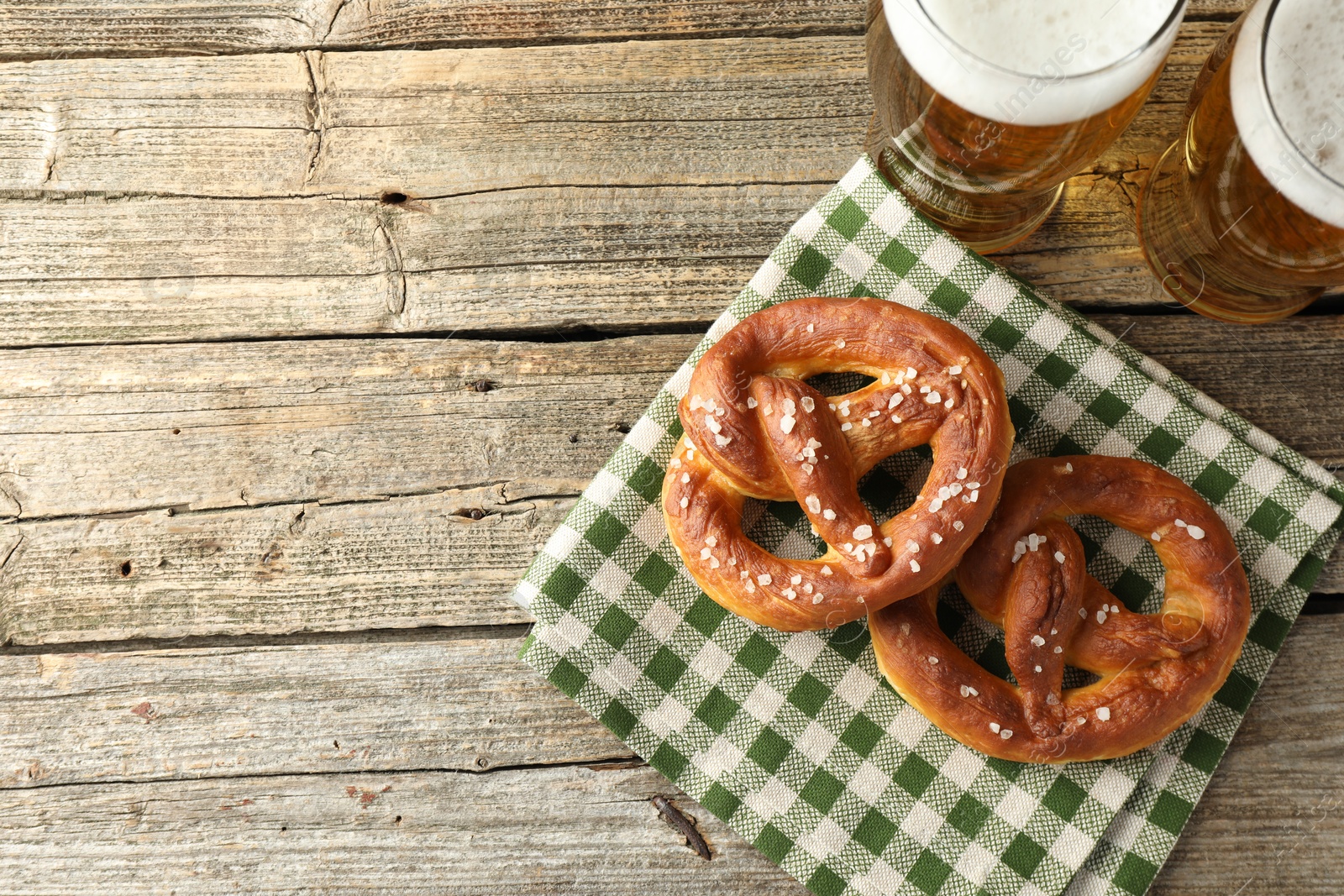 Tasty pretzels and glasses of beer on wooden table, flat lay. Space for text Photo of Tasty pretzels and glasses of beer on wooden table, flat lay. Space for text