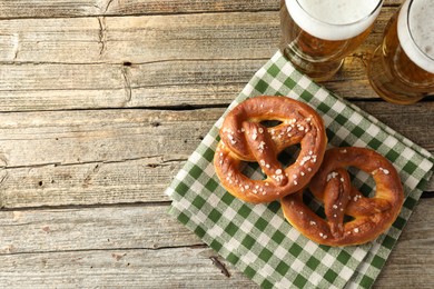 Photo of Tasty pretzels and glasses of beer on wooden table, flat lay. Space for text