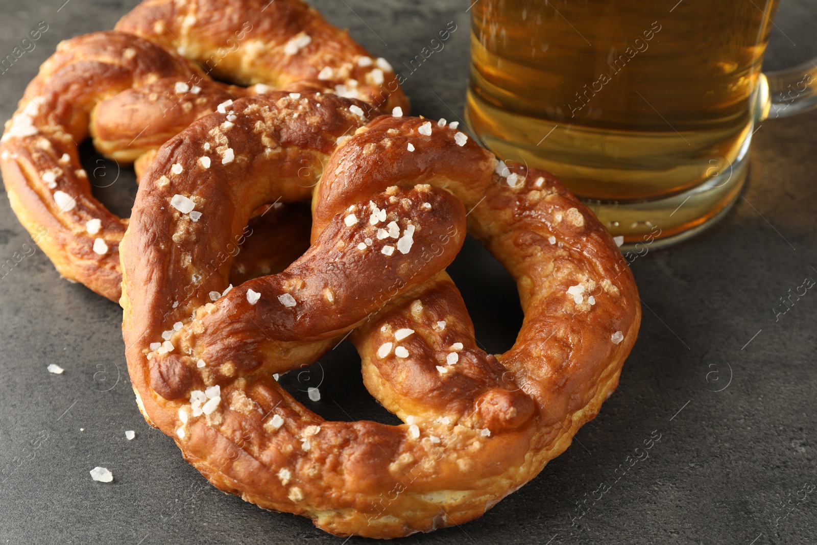 Tasty pretzels and glass of beer on dark textured table, closeup Photo of Tasty pretzels and glass of beer on dark textured table, closeup