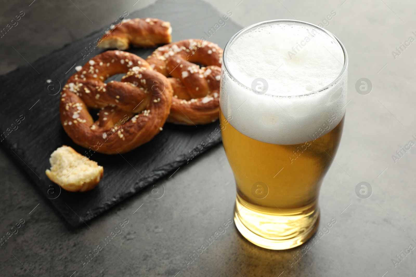 Tasty pretzels and glass of beer on dark textured table, closeup Photo of Tasty pretzels and glass of beer on dark textured table, closeup