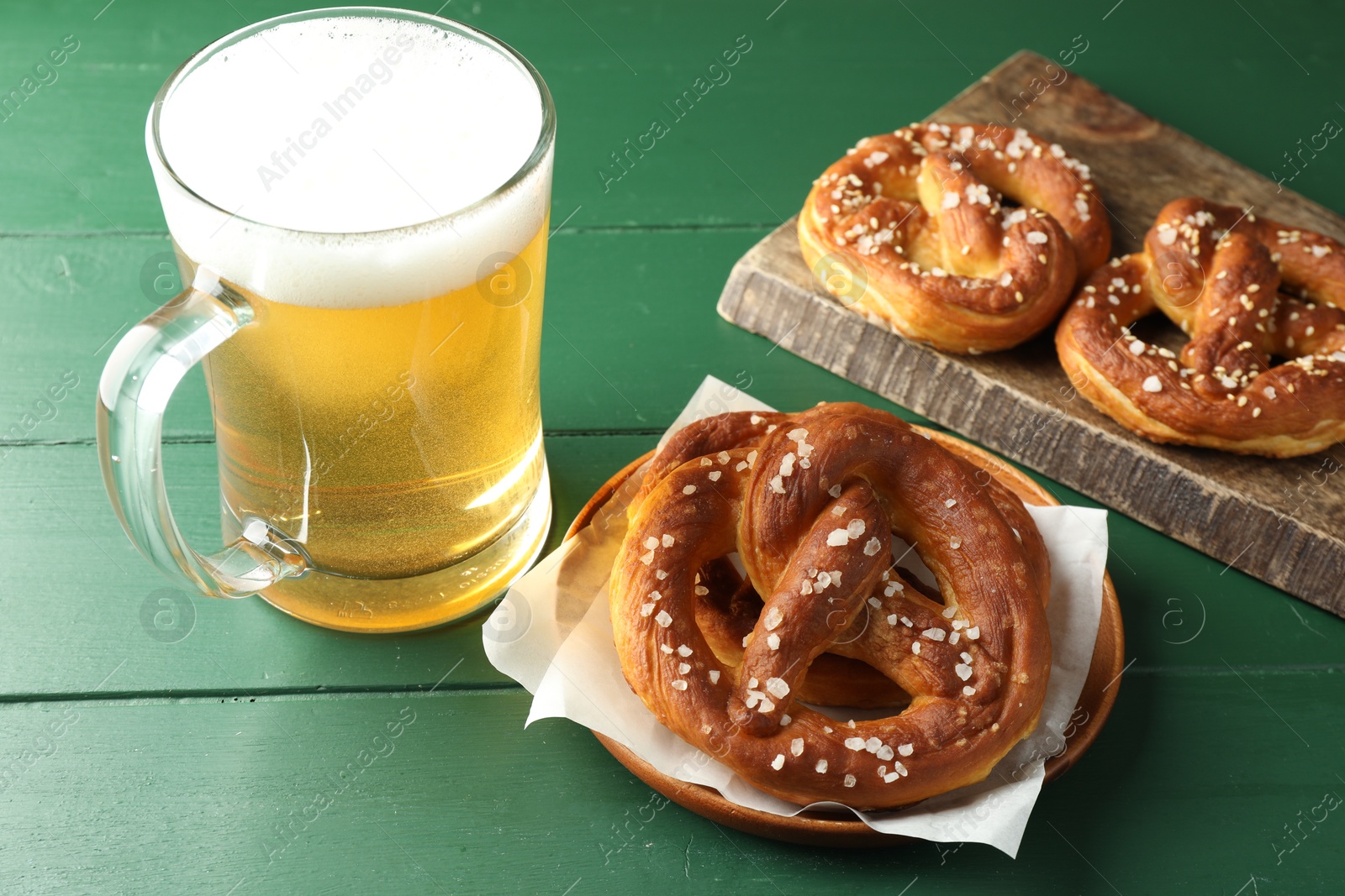 Tasty pretzels and glass of beer on green wooden table, closeup Photo of Tasty pretzels and glass of beer on green wooden table, closeup