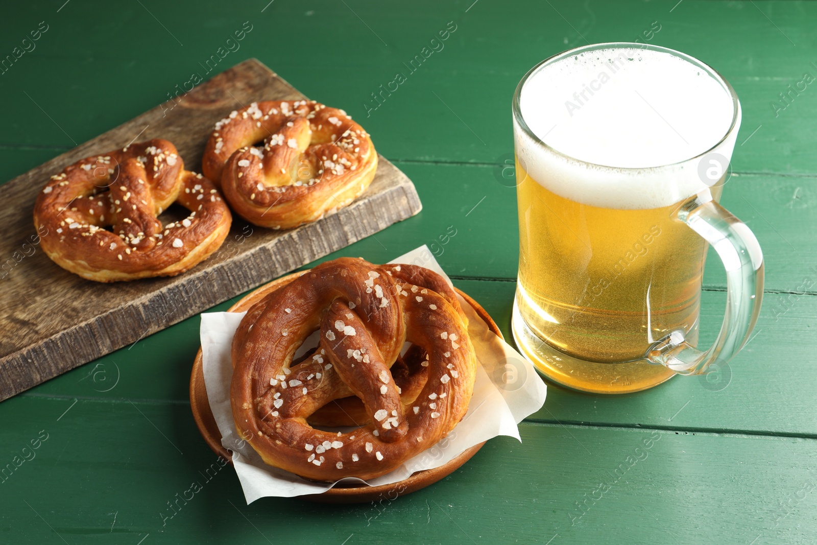 Tasty pretzels and glass of beer on green wooden table, closeup Photo of Tasty pretzels and glass of beer on green wooden table, closeup