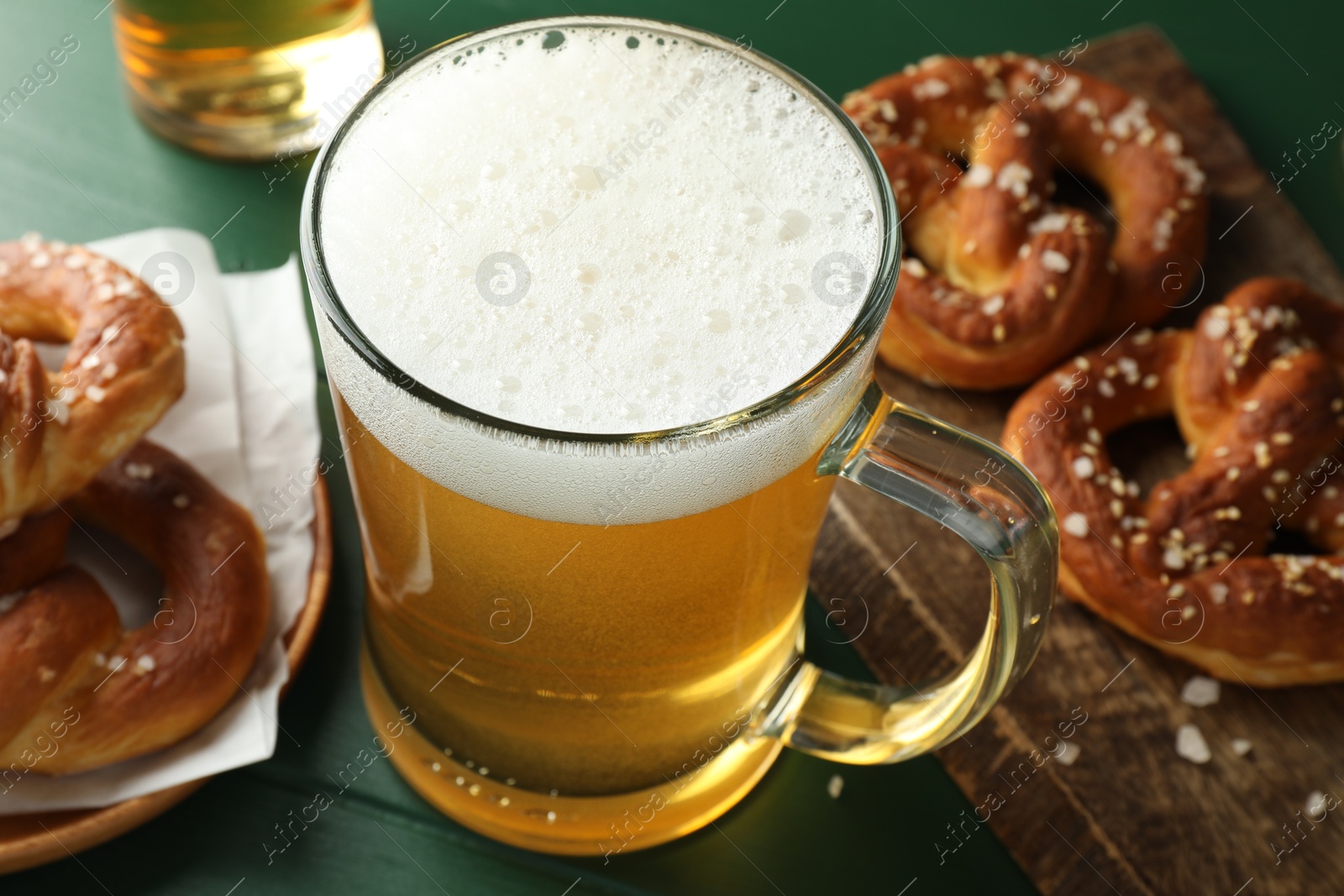 Tasty pretzels and glass of beer on green wooden table, closeup Photo of Tasty pretzels and glass of beer on green wooden table, closeup
