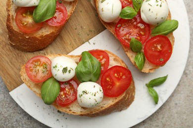 Photo of Tasty sandwiches with mozzarella cheese balls, tomato and basil on grey table, top view