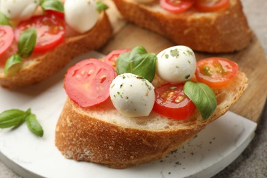 Photo of Tasty sandwiches with mozzarella cheese balls, tomato and basil on grey table, closeup
