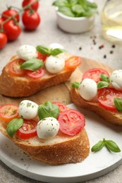 Photo of Tasty sandwiches with mozzarella cheese balls, tomato and basil on grey table, closeup