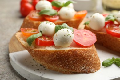 Photo of Tasty sandwiches with mozzarella cheese balls, tomato and basil on grey table, closeup