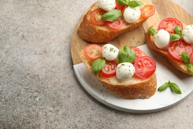 Photo of Tasty sandwiches with mozzarella cheese balls, tomato and basil on grey table. Space for text
