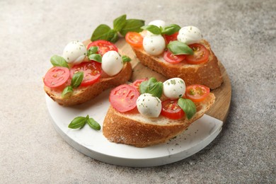 Photo of Tasty sandwiches with mozzarella cheese balls, tomato and basil on grey table