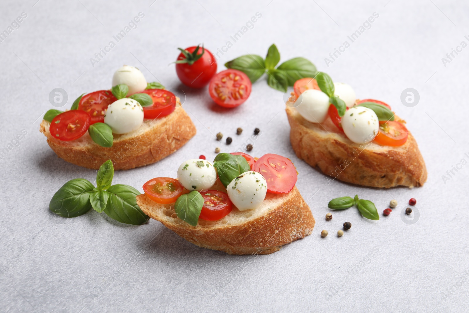 Tasty sandwiches with mozzarella cheese balls, tomato and basil on light grey table Photo of Tasty sandwiches with mozzarella cheese balls, tomato and basil on light grey table