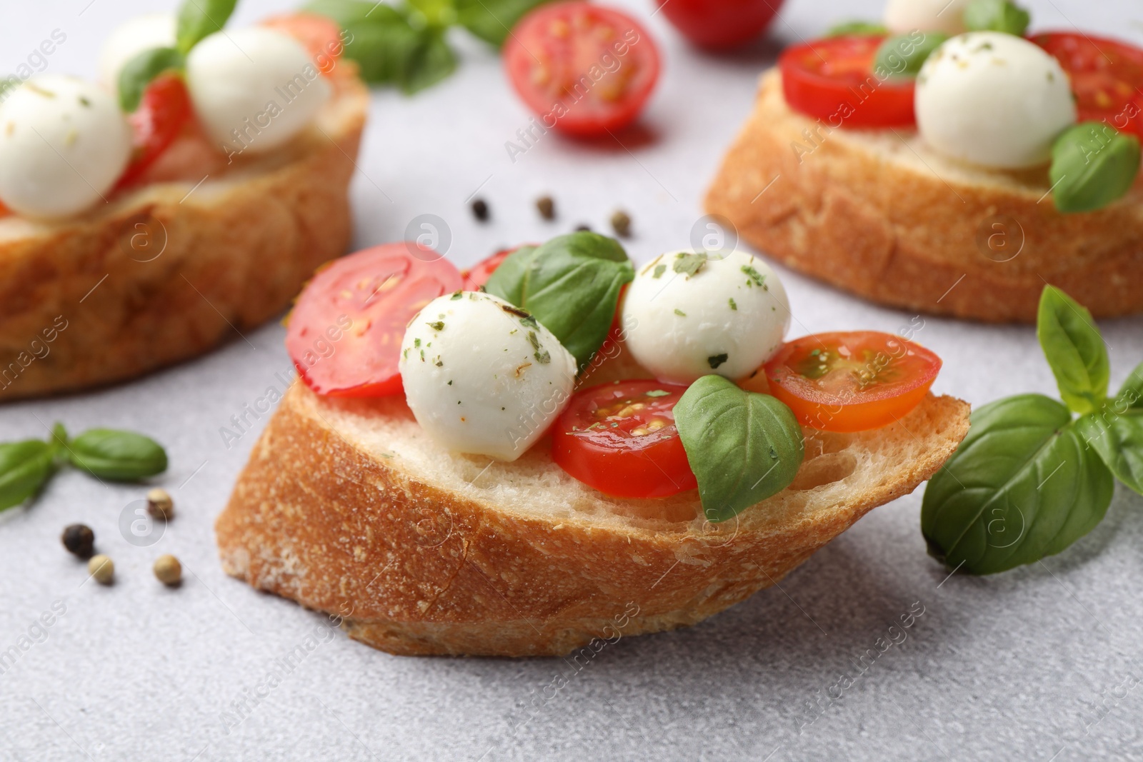 Tasty sandwiches with mozzarella cheese balls, tomato and basil on light grey table, closeup Photo of Tasty sandwiches with mozzarella cheese balls, tomato and basil on light grey table, closeup