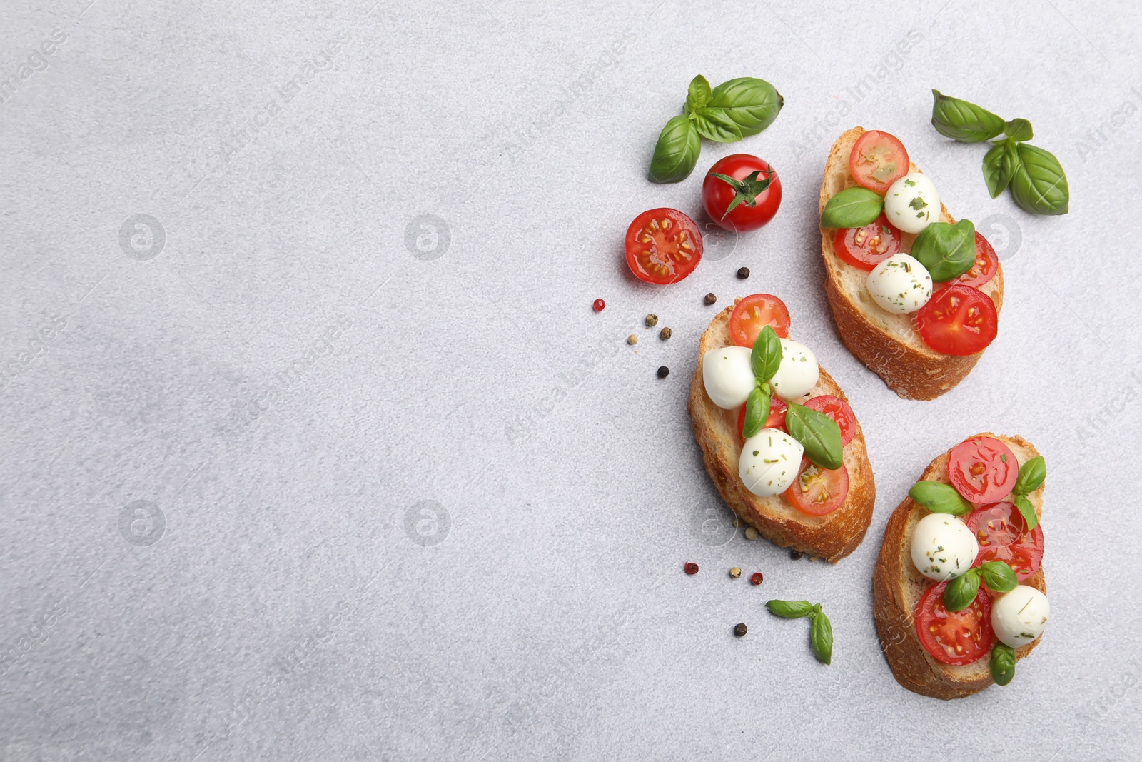 Tasty sandwiches with mozzarella cheese balls, tomato and basil on light grey table, flat lay. Space for text Photo of Tasty sandwiches with mozzarella cheese balls, tomato and basil on light grey table, flat lay. Space for text