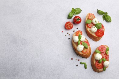 Photo of Tasty sandwiches with mozzarella cheese balls, tomato and basil on light grey table, flat lay. Space for text