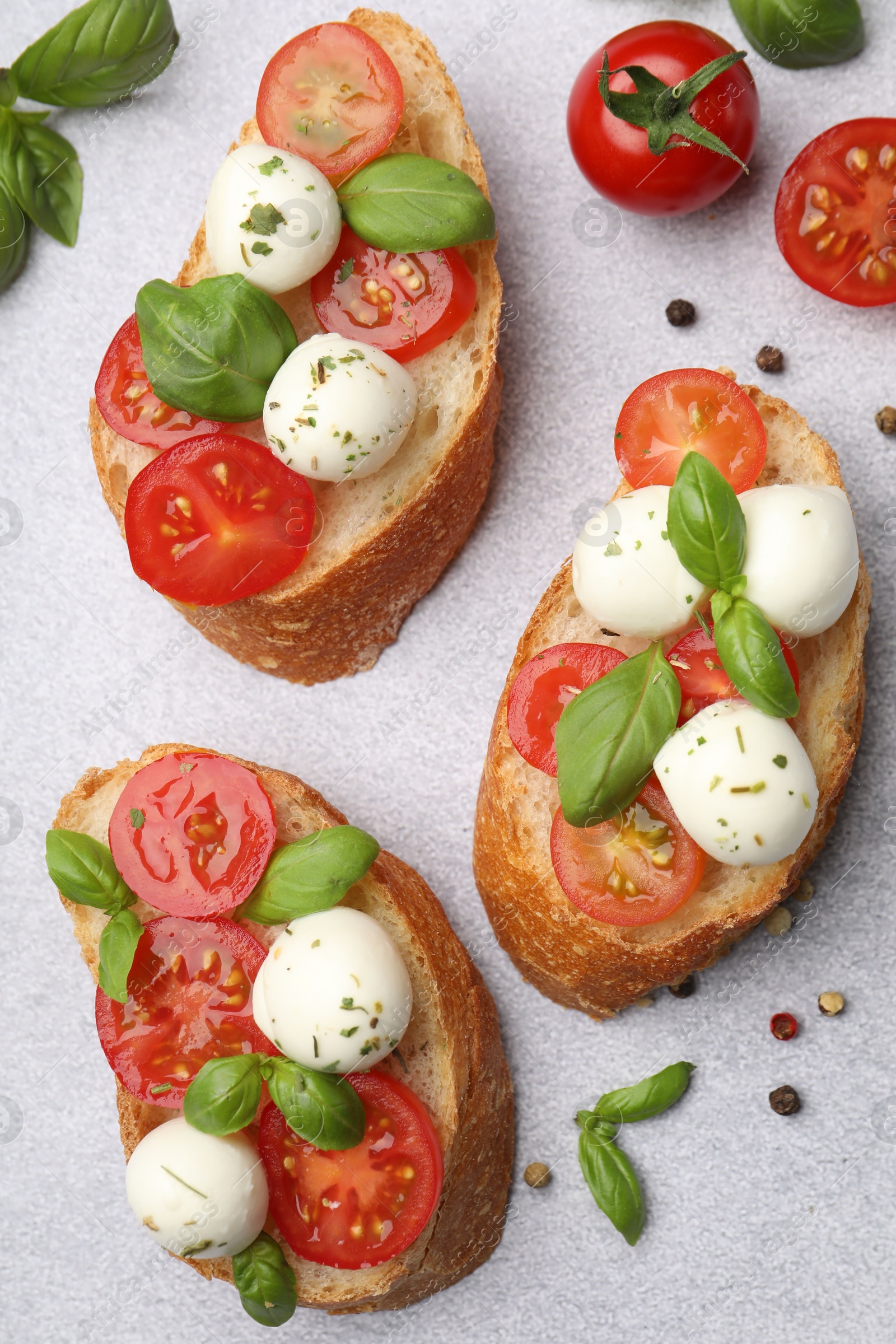 Tasty sandwiches with mozzarella cheese balls, tomato and basil on light grey table, flat lay Photo of Tasty sandwiches with mozzarella cheese balls, tomato and basil on light grey table, flat lay