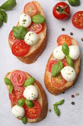 Photo of Tasty sandwiches with mozzarella cheese balls, tomato and basil on light grey table, flat lay