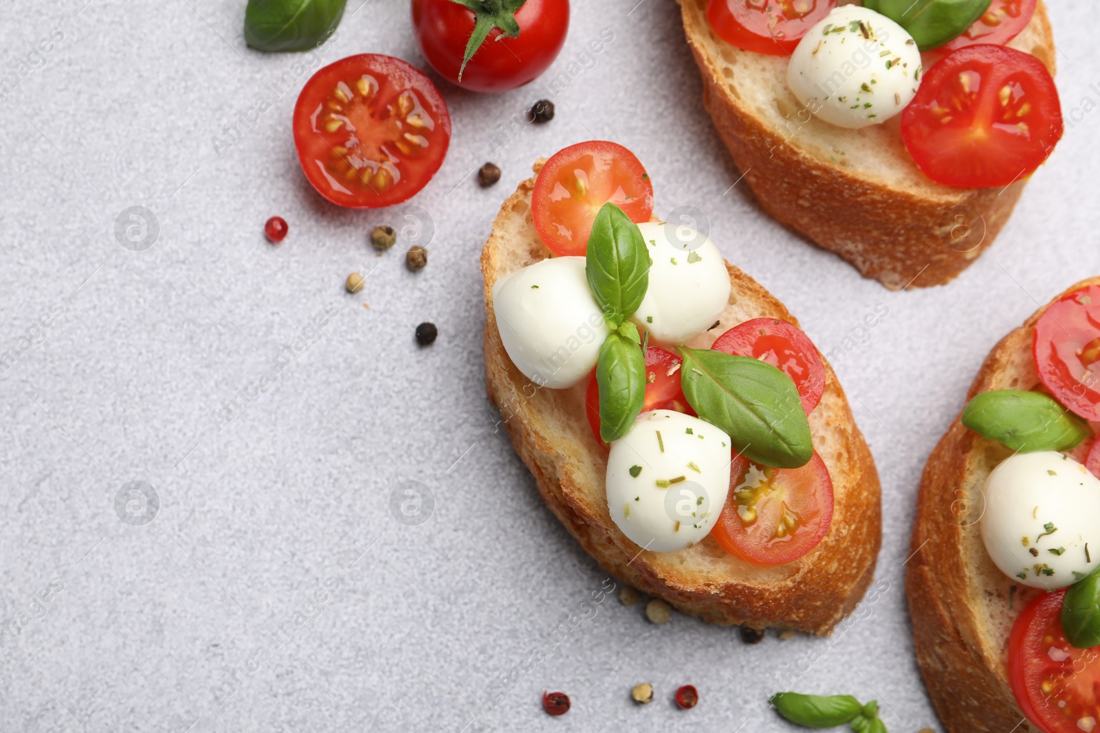 Tasty sandwiches with mozzarella cheese balls, tomato and basil on light grey table, flat lay. Space for text Photo of Tasty sandwiches with mozzarella cheese balls, tomato and basil on light grey table, flat lay. Space for text