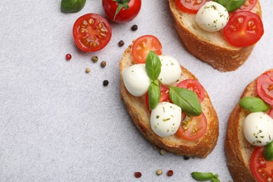 Photo of Tasty sandwiches with mozzarella cheese balls, tomato and basil on light grey table, flat lay. Space for text