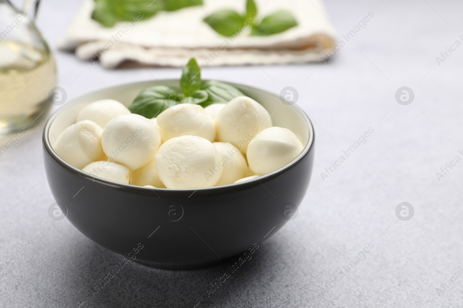 Tasty mozzarella cheese balls and basil on light grey table, closeup. Space for text Photo of Tasty mozzarella cheese balls and basil on light grey table, closeup. Space for text