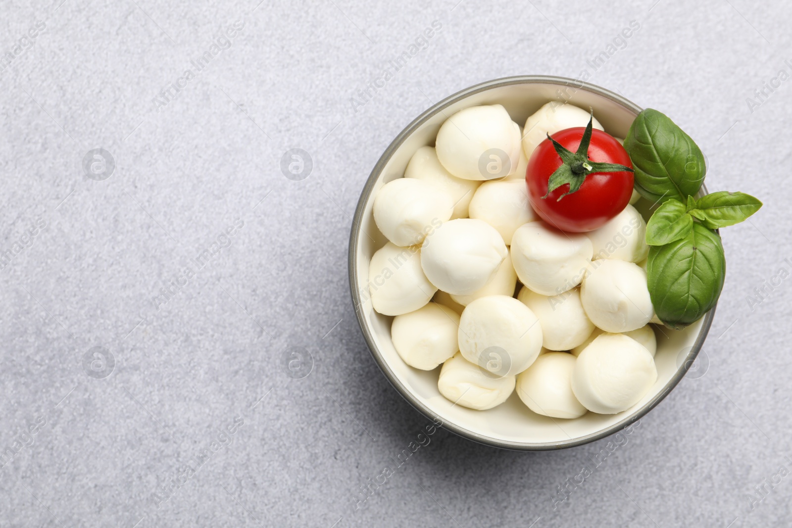 Tasty mozzarella cheese balls, tomato and basil on light grey table, top view. Space for text Photo of Tasty mozzarella cheese balls, tomato and basil on light grey table, top view. Space for text