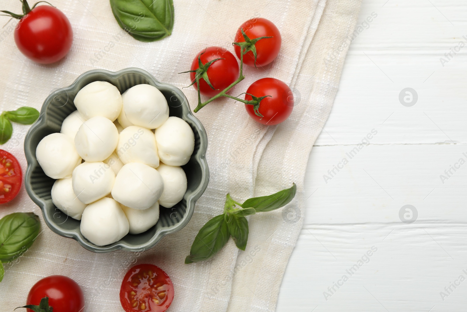 Tasty mozzarella cheese balls, tomatoes and basil on white wooden table, flat lay. Space for text Photo of Tasty mozzarella cheese balls, tomatoes and basil on white wooden table, flat lay. Space for text