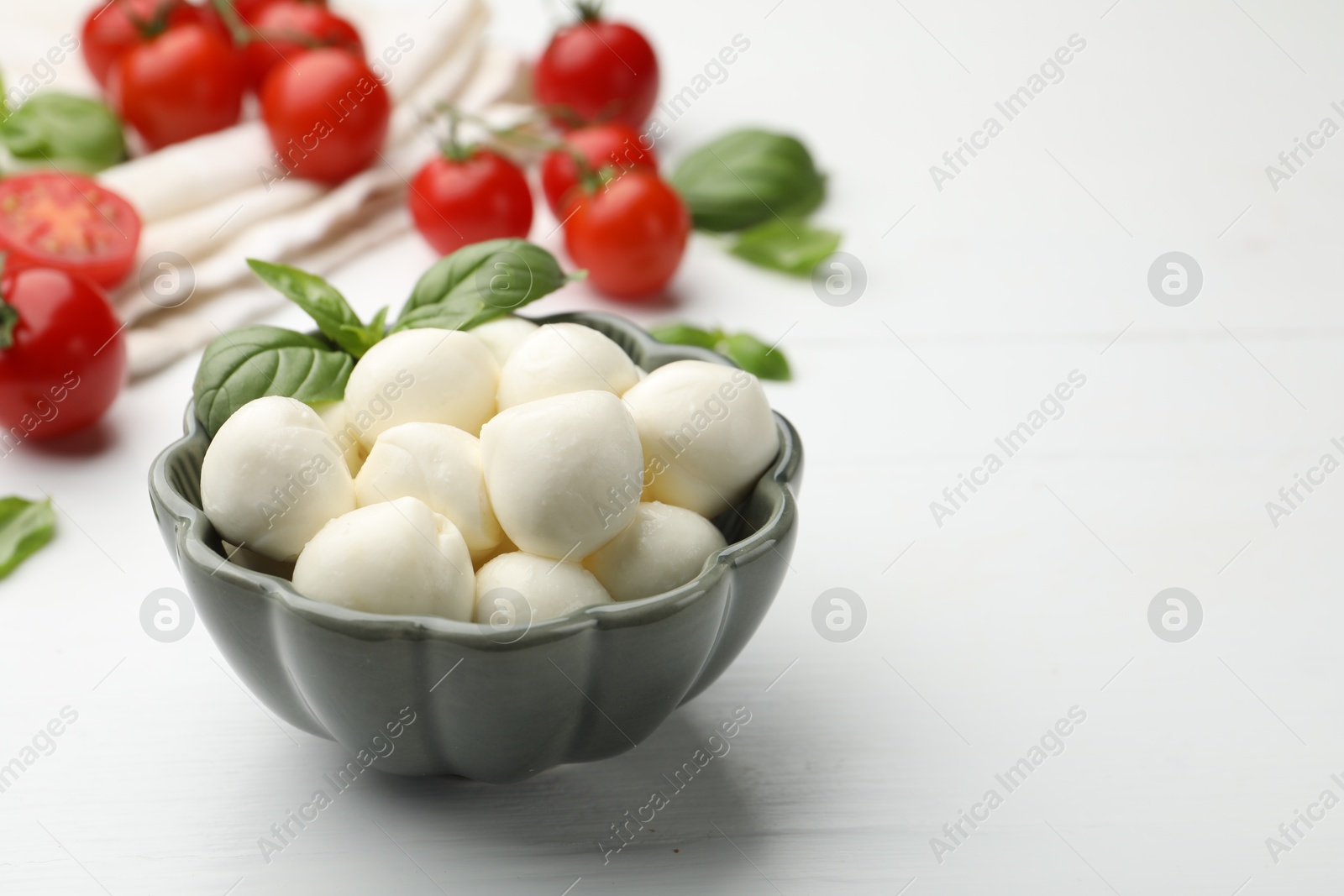 Tasty mozzarella cheese balls, tomatoes and basil on white wooden table, closeup. Space for text Photo of Tasty mozzarella cheese balls, tomatoes and basil on white wooden table, closeup. Space for text
