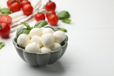Photo of Tasty mozzarella cheese balls, tomatoes and basil on white wooden table, closeup. Space for text