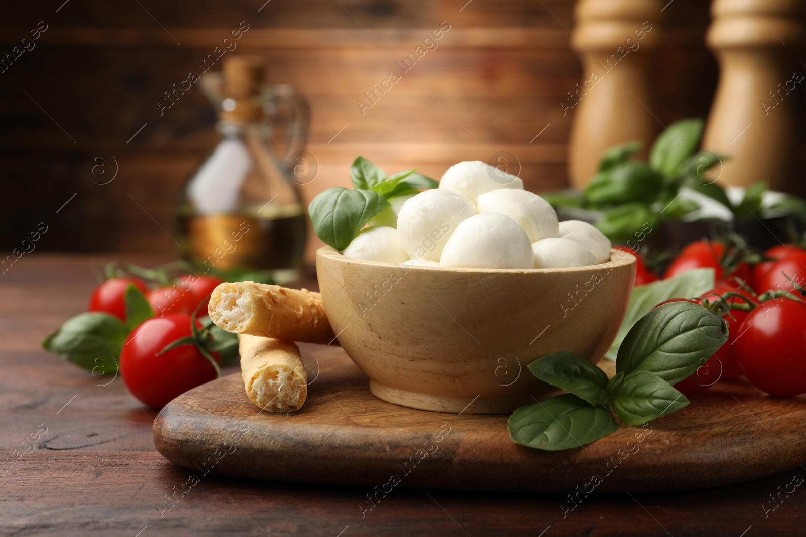 Tasty mozzarella cheese balls, breadsticks, tomatoes and basil on wooden table, closeup Photo of Tasty mozzarella cheese balls, breadsticks, tomatoes and basil on wooden table, closeup