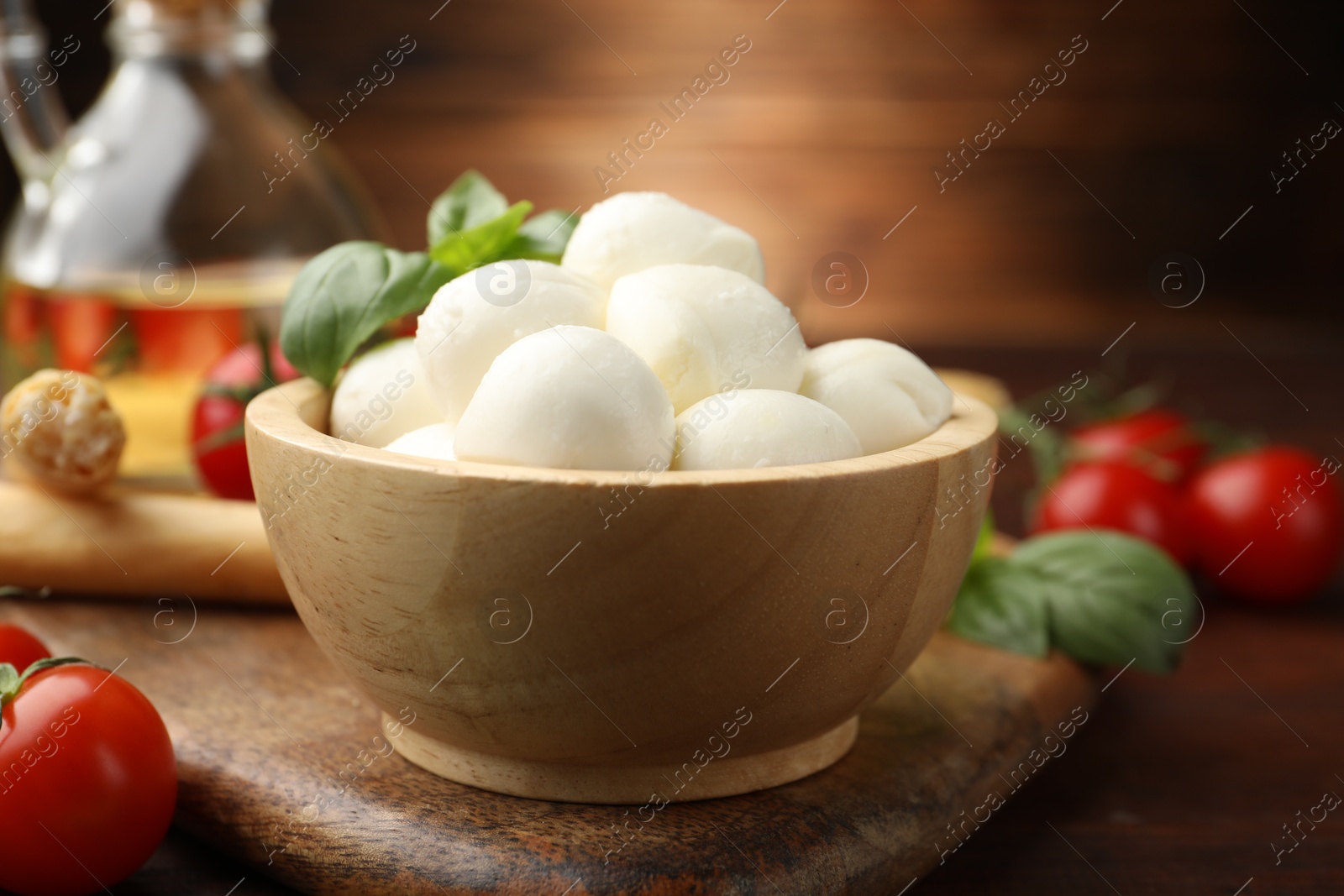 Tasty mozzarella cheese balls, breadsticks, tomatoes and basil on wooden table, closeup Photo of Tasty mozzarella cheese balls, breadsticks, tomatoes and basil on wooden table, closeup
