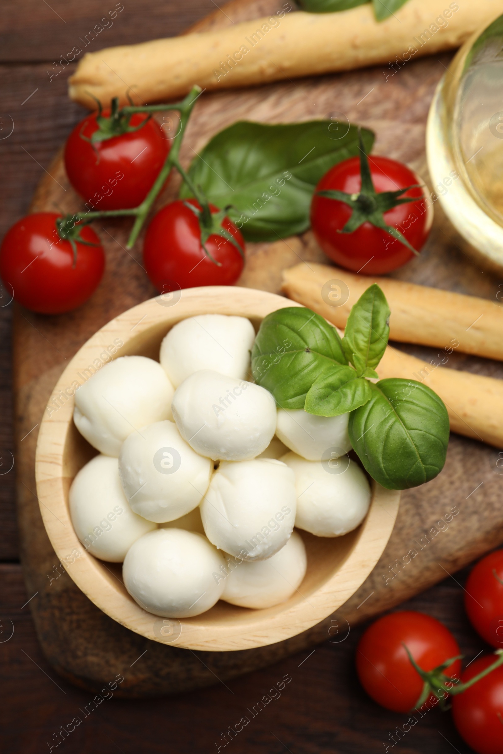 Tasty mozzarella cheese balls, breadsticks, tomatoes and basil on wooden table, flat lay Photo of Tasty mozzarella cheese balls, breadsticks, tomatoes and basil on wooden table, flat lay