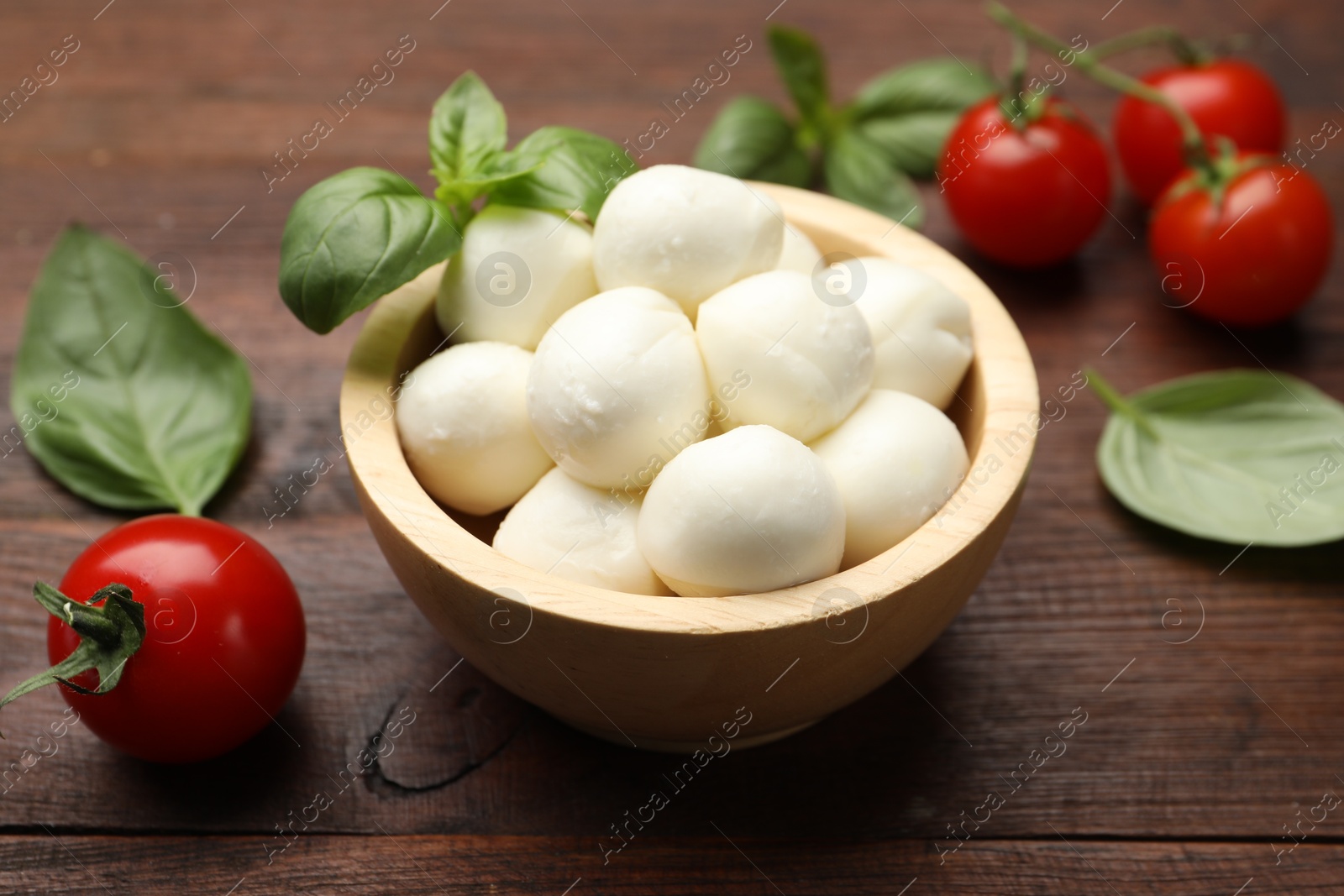 Tasty mozzarella cheese balls, tomatoes and basil on wooden table, closeup Photo of Tasty mozzarella cheese balls, tomatoes and basil on wooden table, closeup