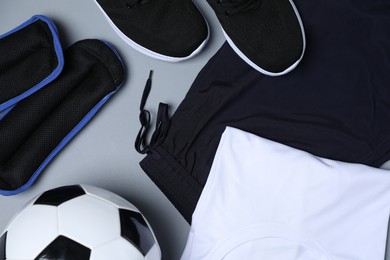Photo of Sportswear, sneakers and soccer ball on grey background, flat lay