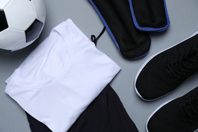 Photo of Sportswear, sneakers and soccer ball on grey background, flat lay